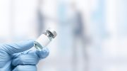 Hand in medical glove holding a vaccine vial